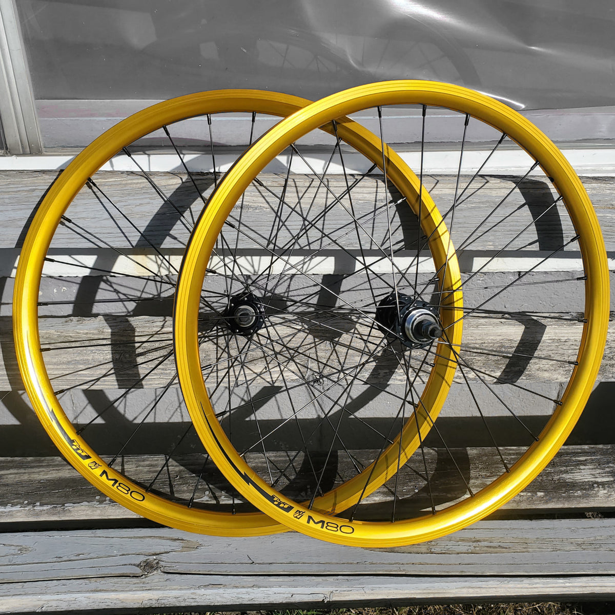 Two yellow bicycle wheels on a wooden surface with a blurred background