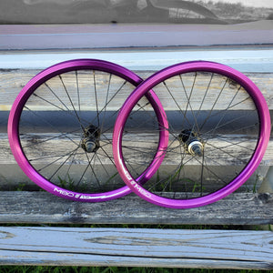 Two purple bicycle wheels on a wooden surface