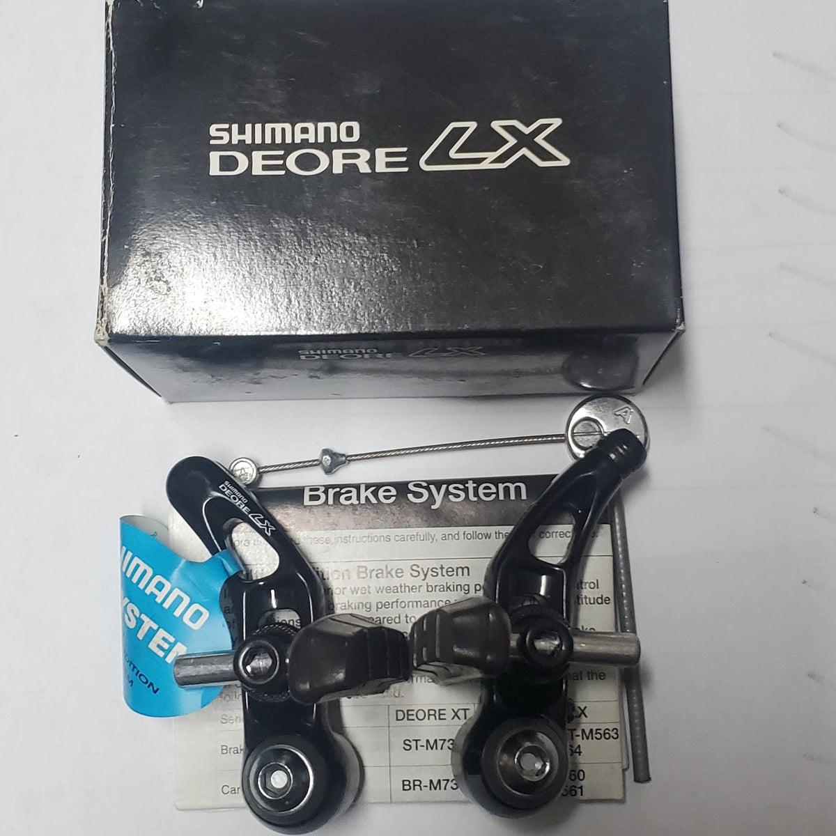 Shimano Deore LX brake system on a white surface with a box in the background.