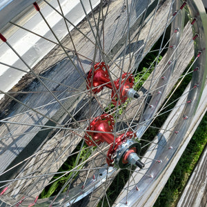 Close-up of a bicycle wheel with red hub on a wooden surface