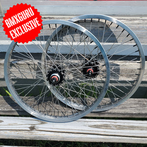 Bicycle wheels on a wooden surface with 'BMXGURU EXCLUSIVE' label.