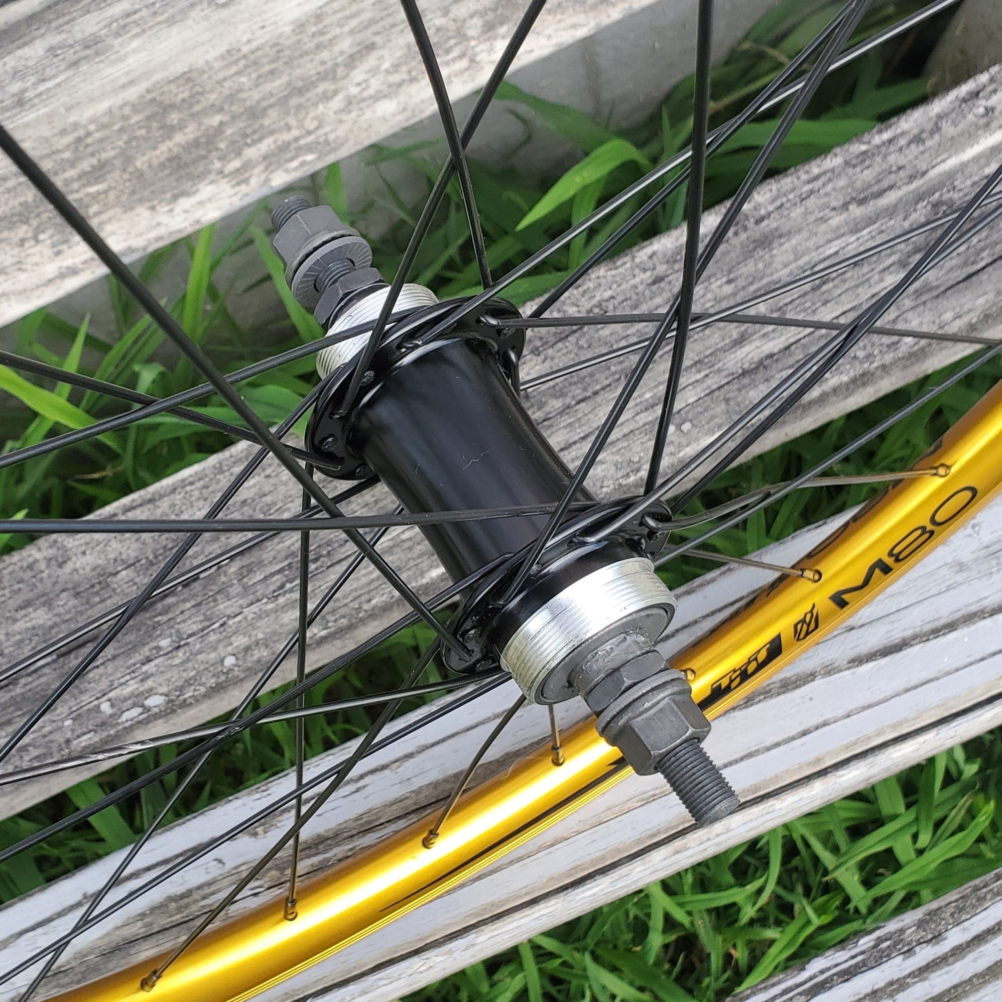 Close-up of a bicycle wheel with a yellow rim on a wooden surface.