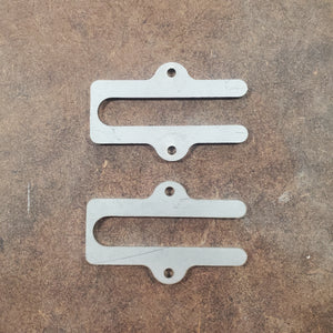 Two metal brackets on a brown textured surface