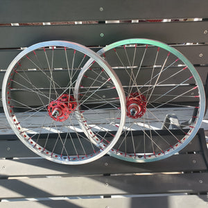 Two bicycle wheels with red hubs against a metallic background