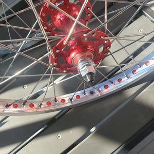 Close-up of a motorcycle wheel with red hub and silver spokes.