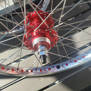 Close-up of a bicycle wheel with a red hub and metal spokes.