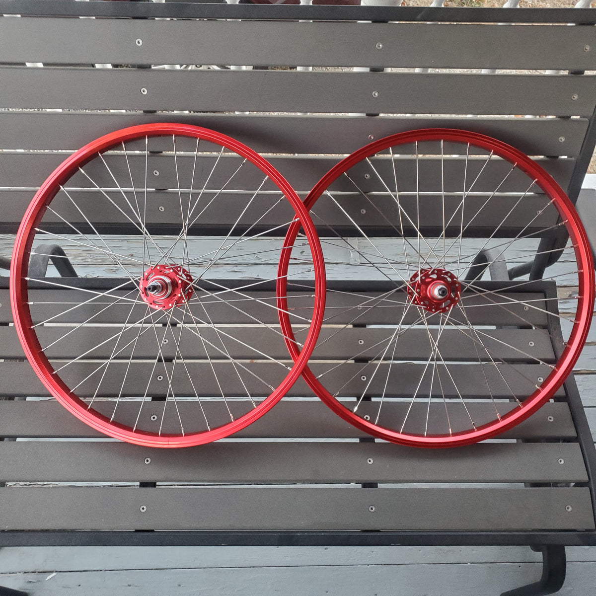 Two red bicycle wheels against a gray wooden background