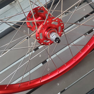 Close-up of a bicycle wheel with red rim and hub on a gray background