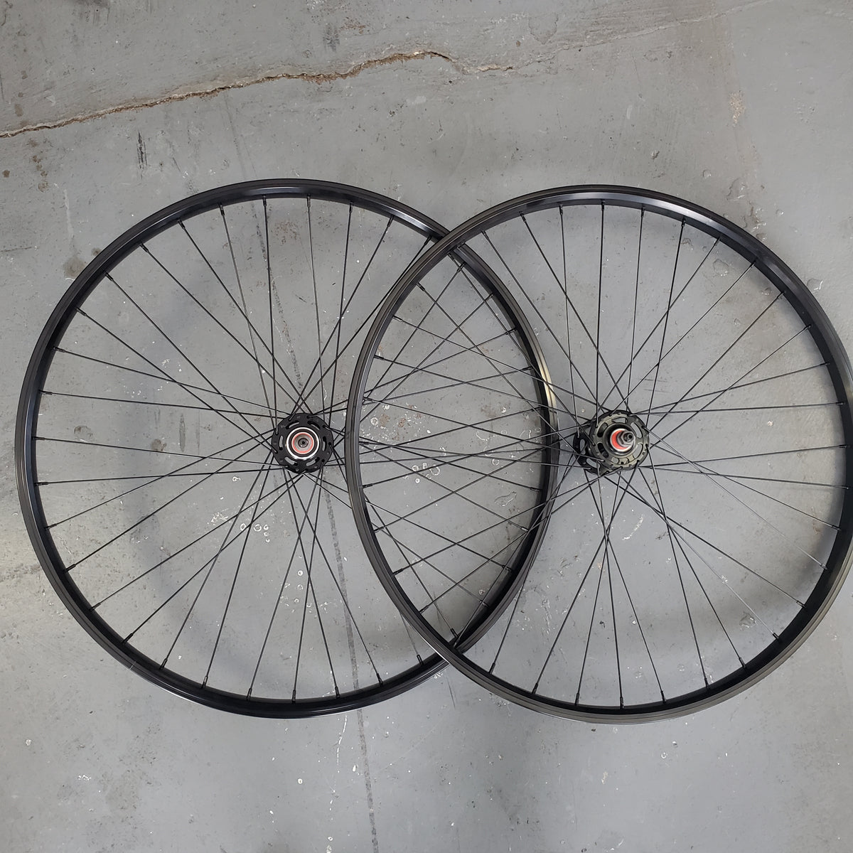 Two bicycle wheels on a gray concrete floor