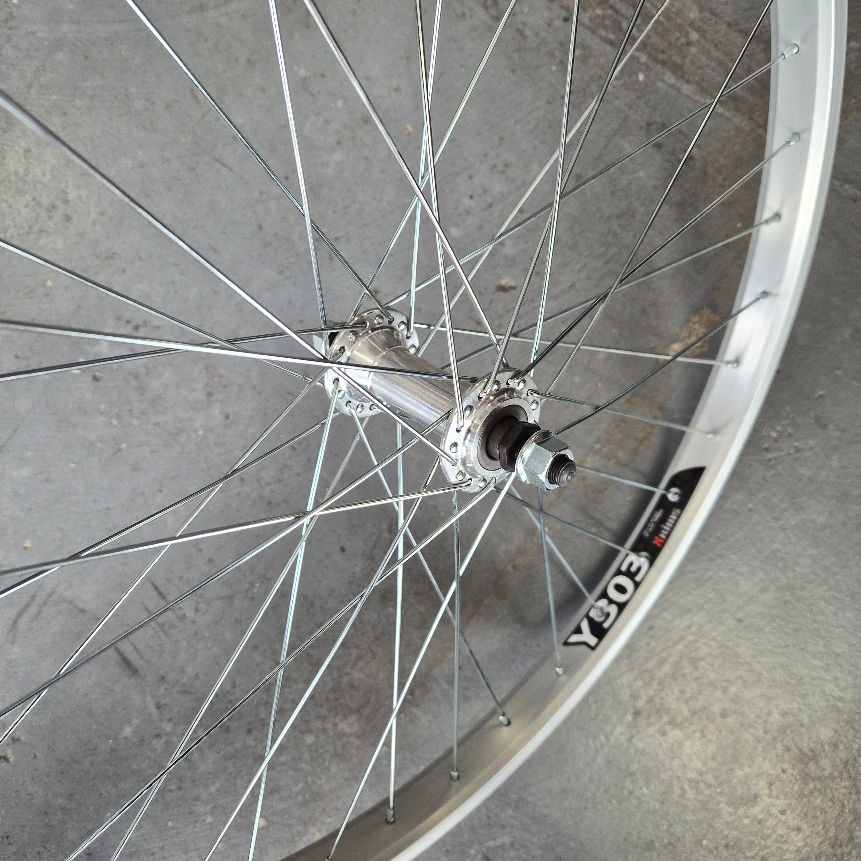 Close-up of a bicycle wheel with a visible brand logo on a concrete surface