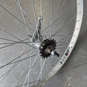 Close-up of a bicycle wheel with a gear on a concrete surface