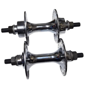 Two chrome bicycle hubs on a white sheet of paper with a wooden surface underneath.