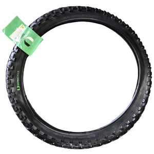 Black tire with a green tag on a concrete surface