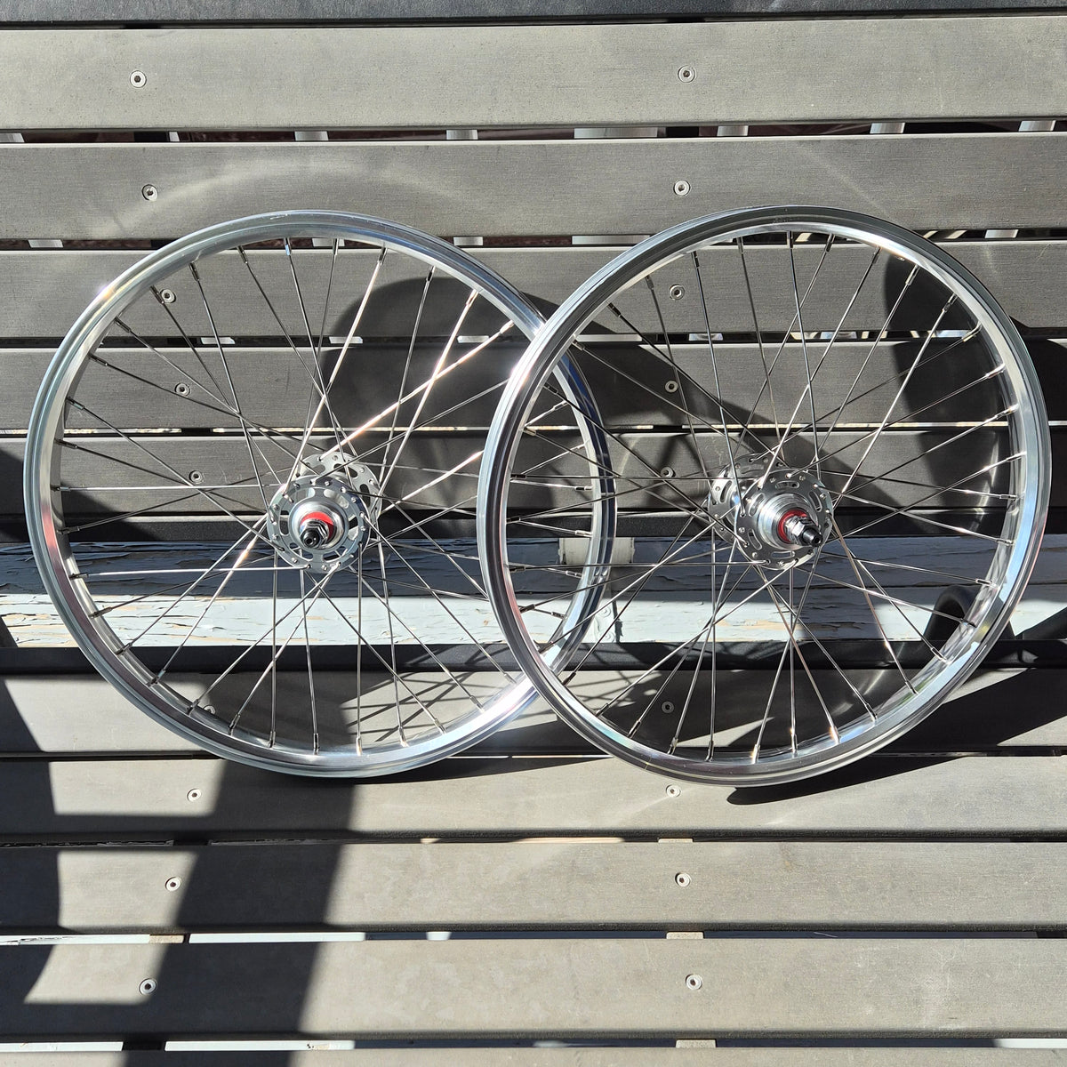 Two bicycle wheels against a wooden slat background
