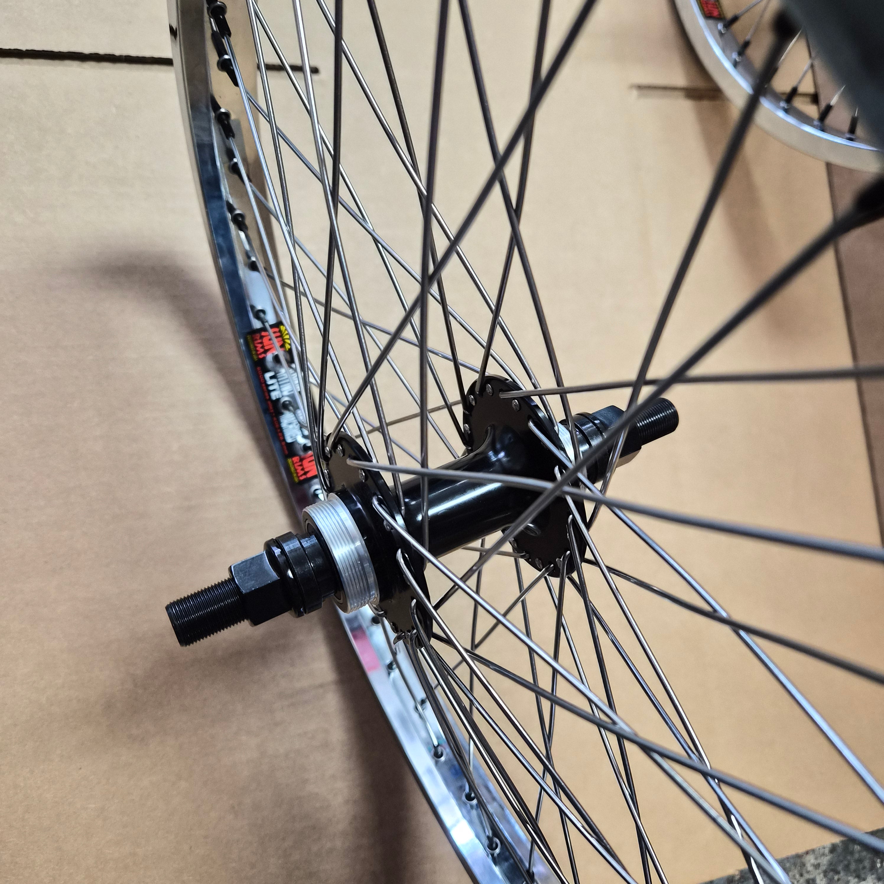 Close-up of a bicycle wheel hub, spokes, and rim resting on a brown cardboard surface.