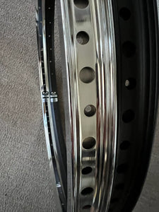 Close-up of a motorcycle rim with a metallic finish on a gray background