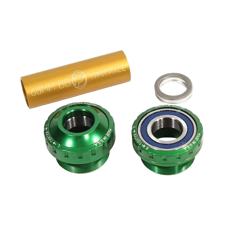 Two green metal bearings and a gold tube spacer on a white background