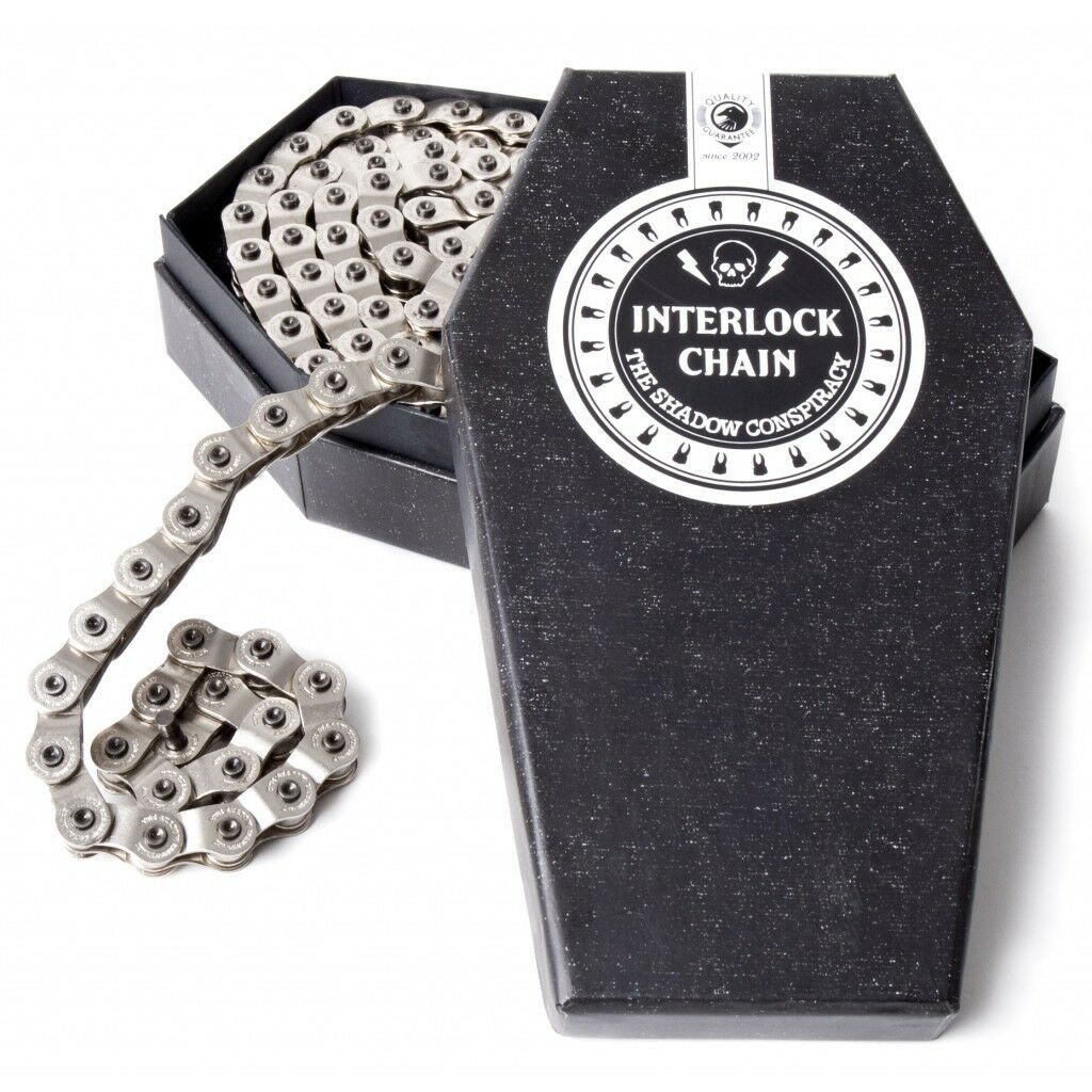 A chrome half-link chain for bicycles, displayed coiled in an open black box with The Shadow Conspiracy branding.